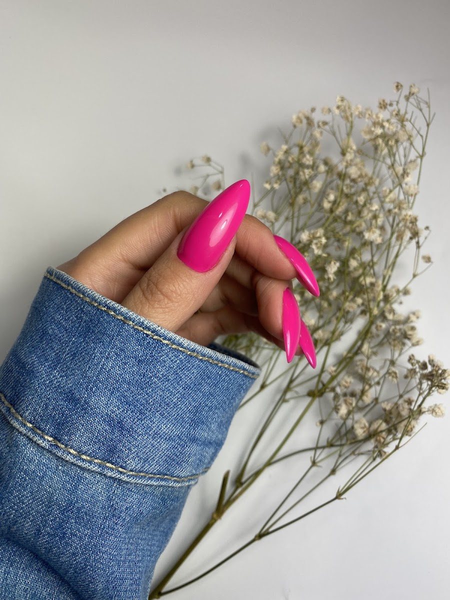 Uñas almendradas en rosa intenso junto a un ramo de paniculata